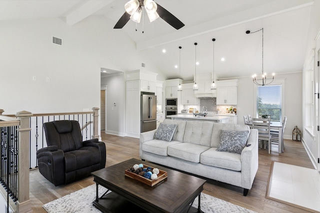 living area featuring light wood-type flooring, visible vents, high vaulted ceiling, beamed ceiling, and ceiling fan with notable chandelier