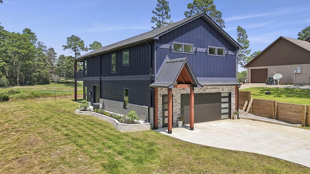 view of front of house with an attached garage, concrete driveway, a front lawn, stone siding, and board and batten siding