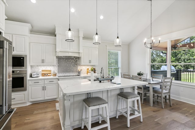 kitchen with a sink, decorative backsplash, white cabinetry, and stainless steel appliances