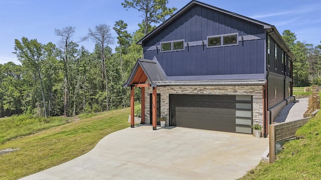 view of side of property with driveway, stone siding, a yard, board and batten siding, and an attached garage