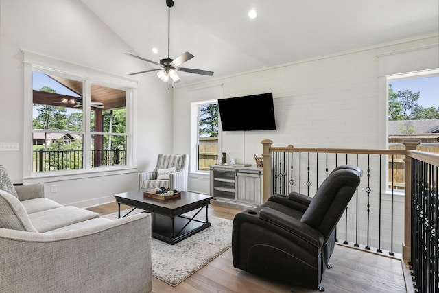 living area featuring lofted ceiling, plenty of natural light, wood finished floors, and ceiling fan