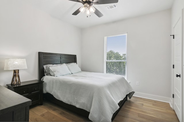 bedroom featuring ceiling fan, visible vents, baseboards, and wood finished floors