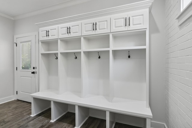 mudroom featuring baseboards, brick wall, and dark wood finished floors