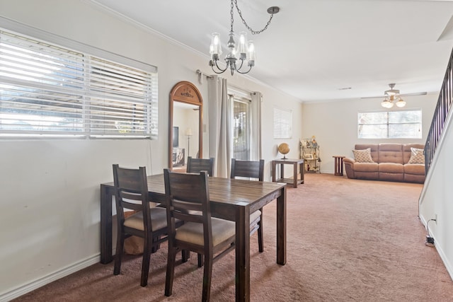 dining space with carpet flooring, ceiling fan with notable chandelier, and crown molding