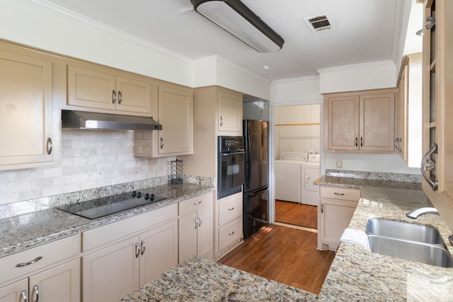 kitchen with black appliances, sink, hardwood / wood-style flooring, independent washer and dryer, and ornamental molding