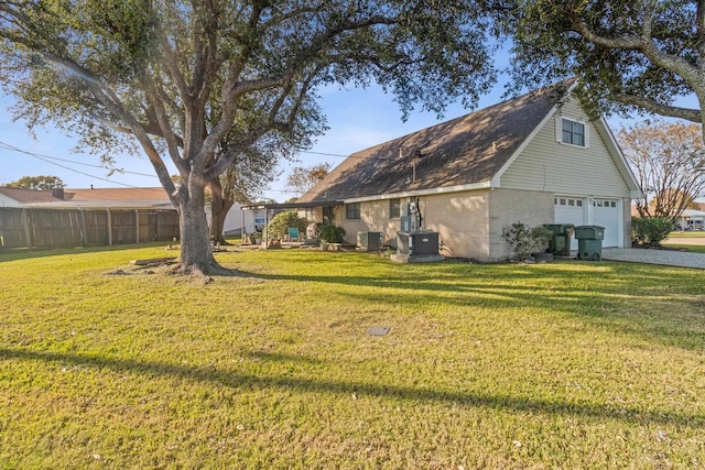 view of side of home with a garage, cooling unit, and a lawn