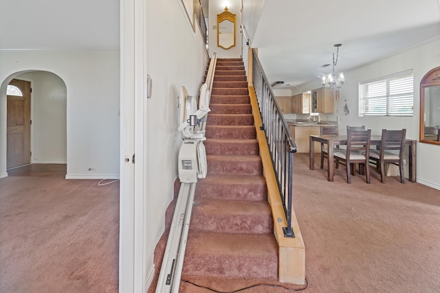 stairway with carpet and a chandelier