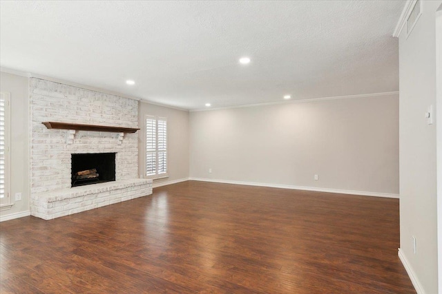 unfurnished living room with a fireplace, a textured ceiling, dark hardwood / wood-style flooring, and crown molding