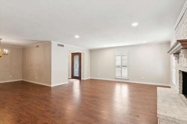 unfurnished living room featuring dark hardwood / wood-style flooring, a fireplace, ornamental molding, and a notable chandelier