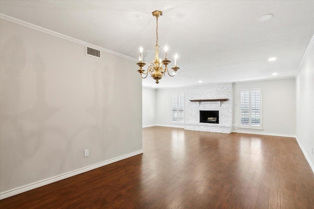 unfurnished living room with a chandelier, hardwood / wood-style floors, a stone fireplace, and ornamental molding