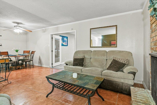 living room featuring tile patterned floors, crown molding, ceiling fan, a textured ceiling, and a fireplace