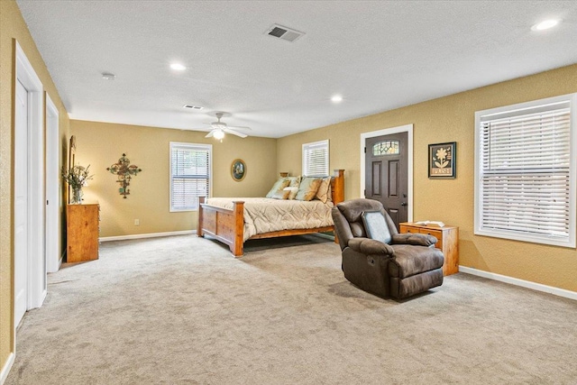 carpeted bedroom featuring ceiling fan and a textured ceiling