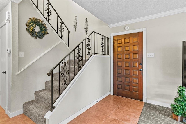 entryway featuring a textured ceiling, ornamental molding, and light tile patterned flooring