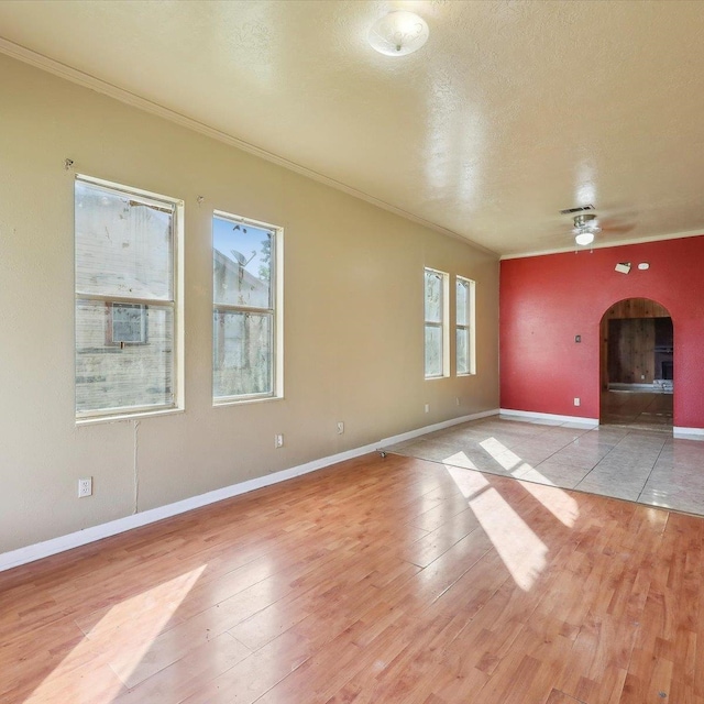 1710 17th St, Port Arthur, TX 77640 - unfurnished living room featuring light wood-type flooring, arched walkways, ceiling fan, and ornamental molding