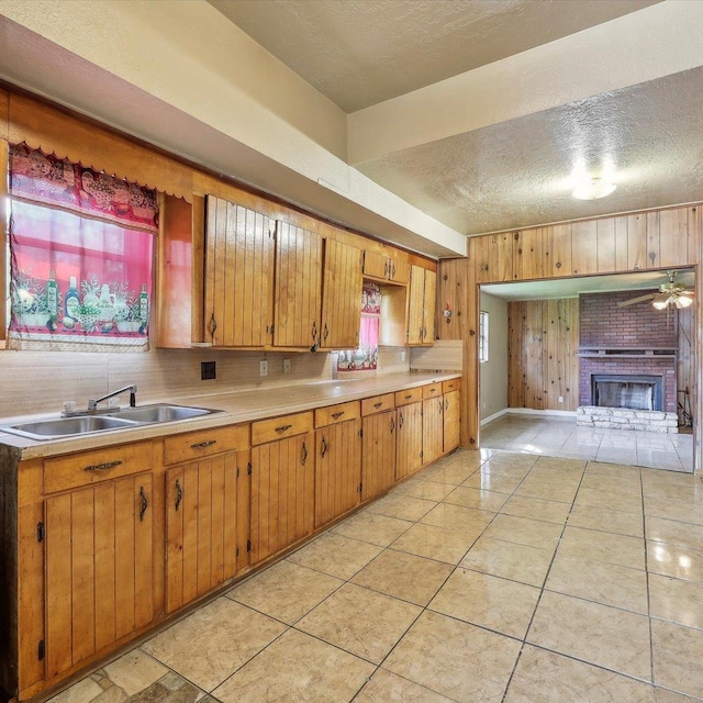 1710 17th St, Port Arthur, TX 77640 - kitchen featuring a fireplace, wooden walls, light countertops, a textured ceiling, and a sink