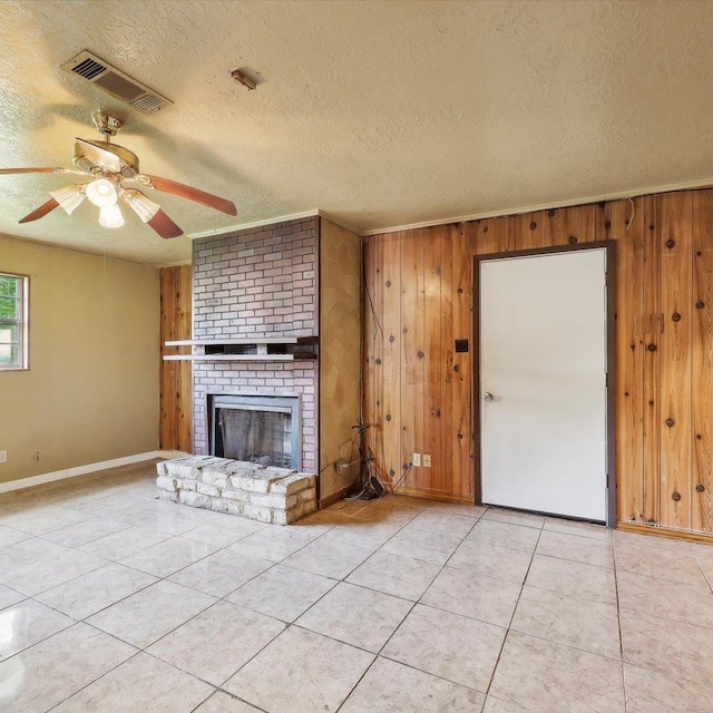 1710 17th St, Port Arthur, TX 77640 - unfurnished living room featuring visible vents, a textured ceiling, tile patterned flooring, and wooden walls