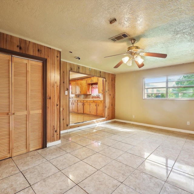 1710 17th St, Port Arthur, TX 77640 - unfurnished living room with light tile patterned flooring, wood walls, visible vents, and baseboards