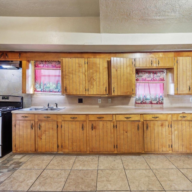 1710 17th St, Port Arthur, TX 77640 - kitchen with decorative backsplash, gas stove, light countertops, a sink, and under cabinet range hood