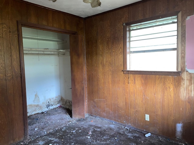 unfurnished bedroom with a closet and wood walls