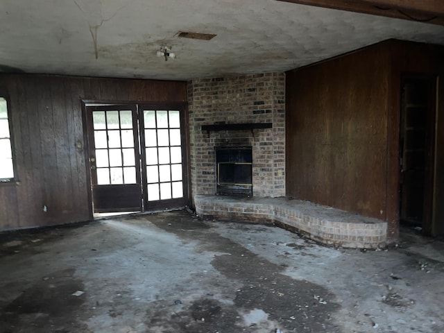 unfurnished living room with wood walls and a fireplace