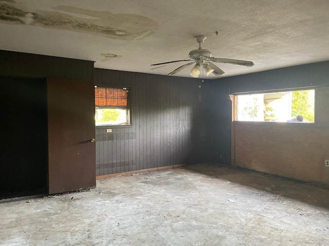 spare room with wood walls and ceiling fan