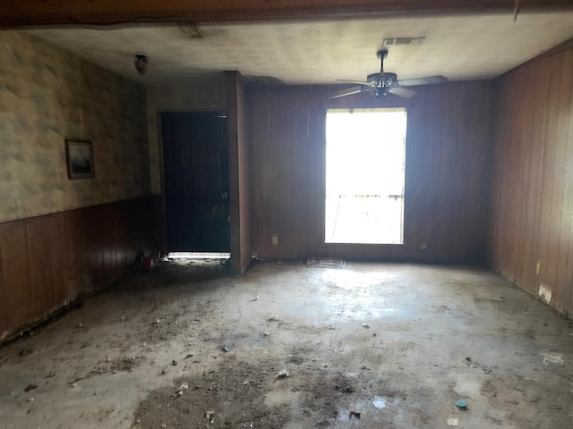 spare room featuring ceiling fan and wooden walls