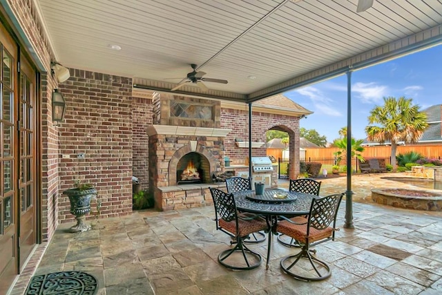 view of patio with area for grilling, ceiling fan, and an outdoor stone fireplace