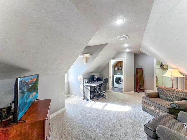 office area featuring washer / dryer, a textured ceiling, light colored carpet, and vaulted ceiling