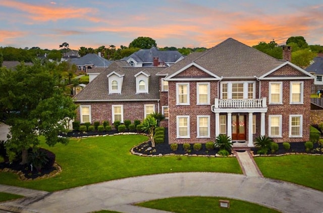 view of front of home with a yard and a balcony