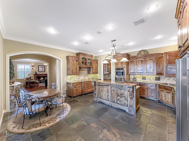 kitchen with pendant lighting, decorative backsplash, ornamental molding, appliances with stainless steel finishes, and a kitchen island