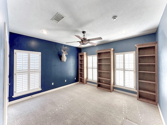 unfurnished bedroom featuring ceiling fan, light colored carpet, and a textured ceiling