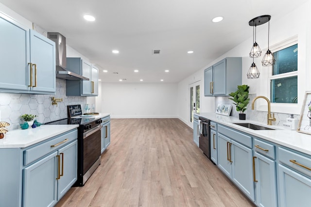 kitchen featuring sink, wall chimney exhaust hood, backsplash, appliances with stainless steel finishes, and light wood-type flooring