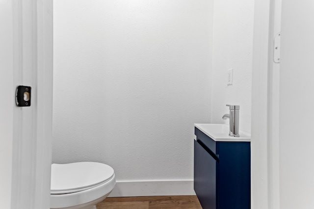 bathroom with hardwood / wood-style floors, vanity, and toilet