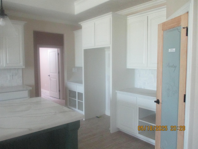 9145 Bellflower St, Beaumont, TX 77713 - kitchen with white cabinets, light wood-type flooring, crown molding, and light countertops