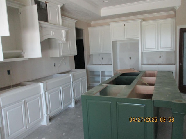 9145 Bellflower St, Beaumont, TX 77713 - kitchen with concrete flooring, crown molding, white cabinets, a tray ceiling, and a kitchen island