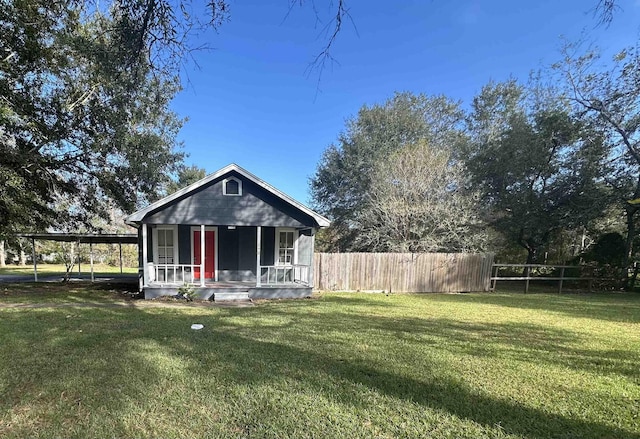 back of property with a porch, a carport, and a lawn