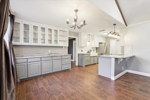 kitchen featuring a kitchen bar, hanging light fixtures, stainless steel refrigerator, gray cabinets, and white cabinets