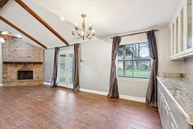 unfurnished living room featuring vaulted ceiling with beams, ceiling fan with notable chandelier, a fireplace, and dark hardwood / wood-style floors