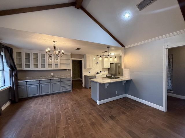 kitchen with kitchen peninsula, stainless steel fridge, pendant lighting, a notable chandelier, and beam ceiling