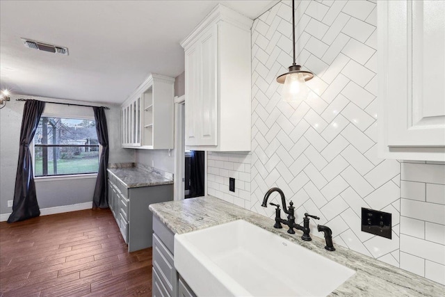 kitchen featuring white cabinetry, light stone countertops, sink, and pendant lighting