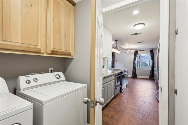 laundry area featuring an inviting chandelier, cabinets, dark hardwood / wood-style flooring, and washing machine and dryer