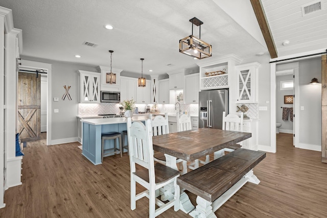 109 Ocean View Dr, Crystal Beach, TX 77650 - dining area featuring a barn door, visible vents, dark wood finished floors, and baseboards