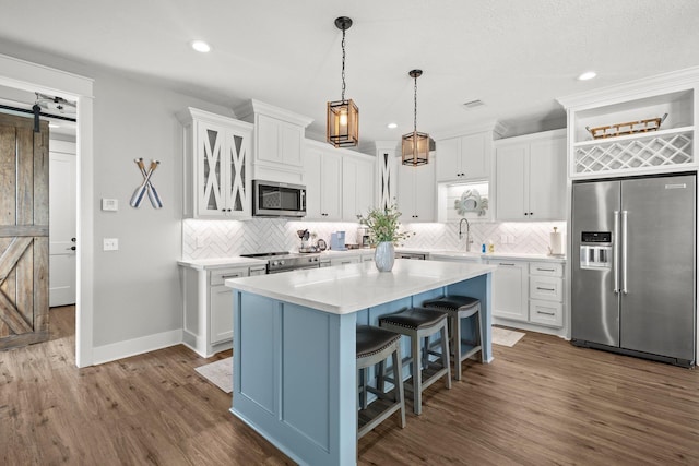 109 Ocean View Dr, Crystal Beach, TX 77650 - kitchen with a barn door, stainless steel appliances, tasteful backsplash, dark wood-type flooring, and a kitchen island