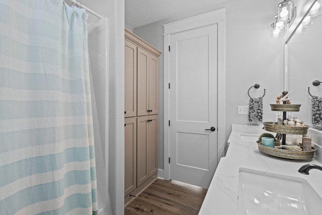 109 Ocean View Dr, Crystal Beach, TX 77650 - full bathroom with curtained shower, wood finished floors, double vanity, and a sink