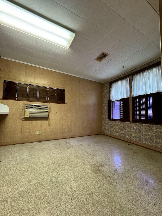 spare room with a wall unit AC and wooden walls