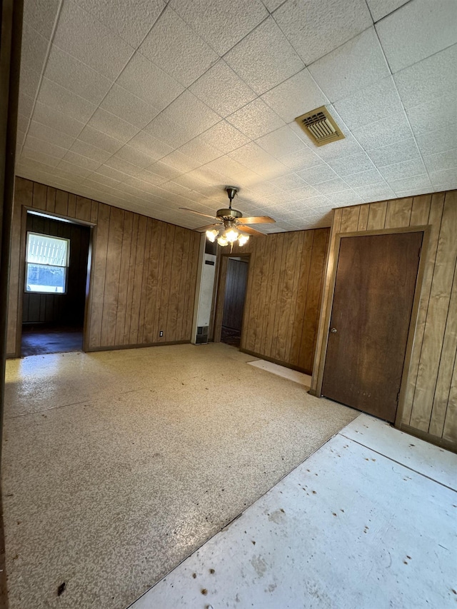 unfurnished room featuring ceiling fan and wood walls