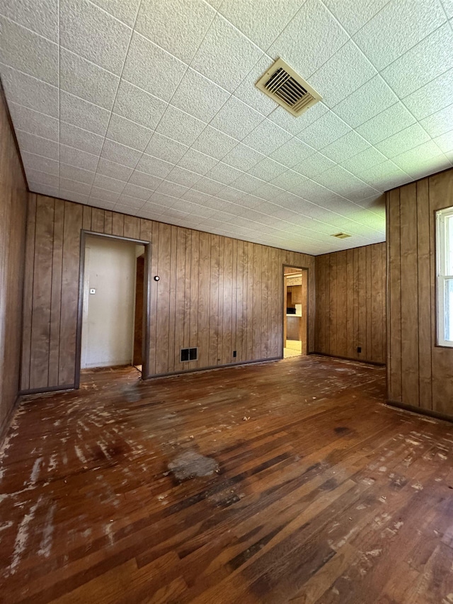 unfurnished living room featuring wood walls and dark wood-type flooring