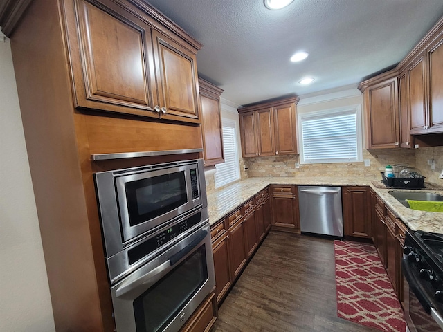 kitchen featuring light stone countertops, sink, stainless steel appliances, dark hardwood / wood-style flooring, and decorative backsplash