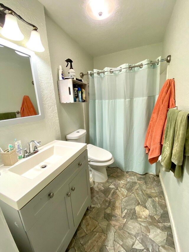 bathroom featuring a shower with curtain, vanity, toilet, and a textured ceiling