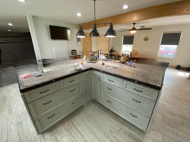 kitchen featuring kitchen peninsula, ceiling fan, light hardwood / wood-style flooring, green cabinetry, and hanging light fixtures